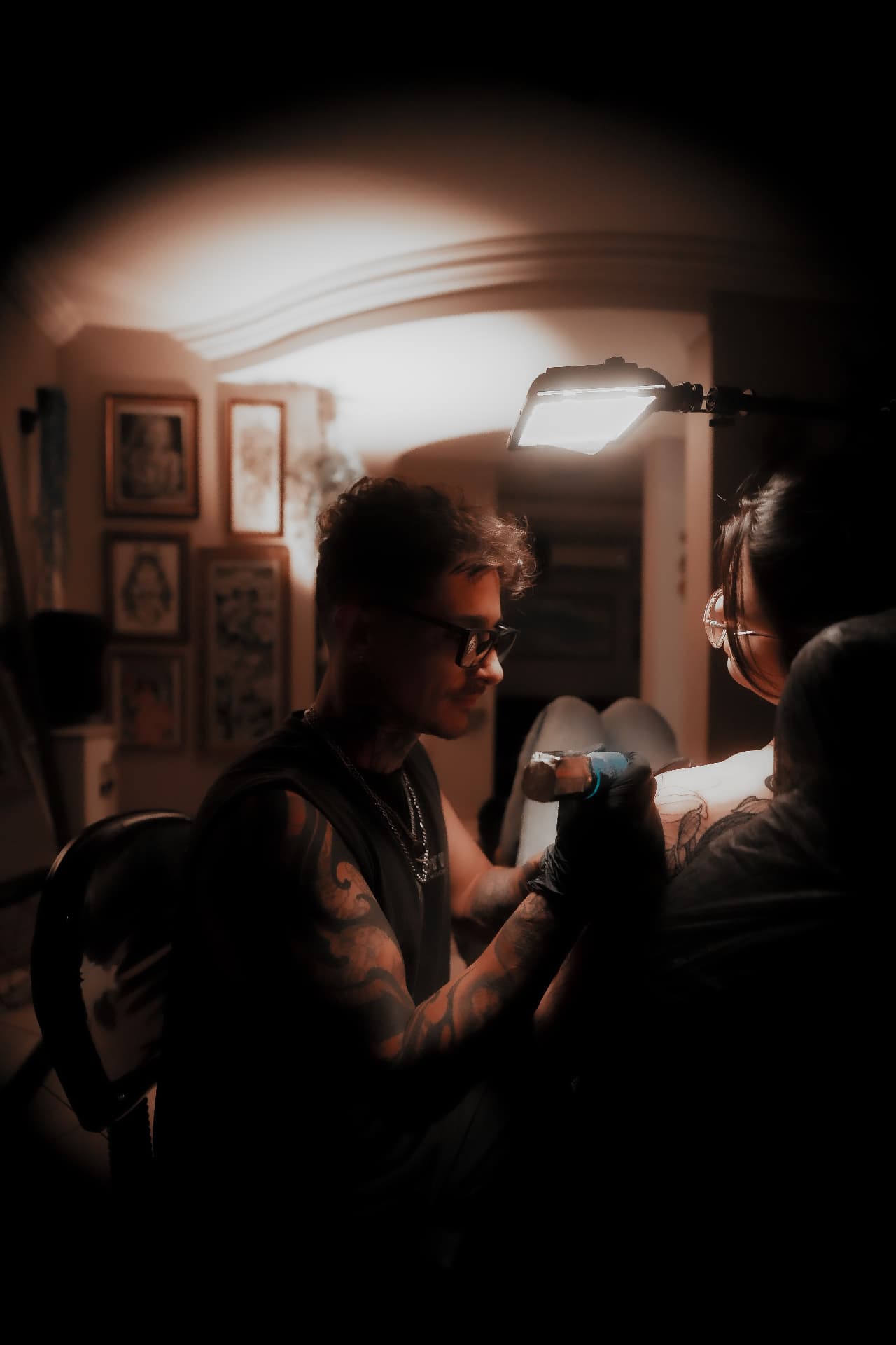 Roger Santos tatuando sob a luminária do estúdio